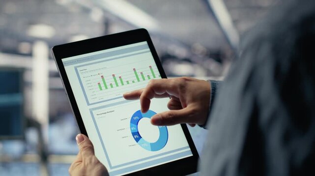 Close up of data center employee checking infrastructure diagnostics graphs on tablet screen. IT specialist on industrial platform in server room examining data charts during system audit, camera B - Powered by Adobe