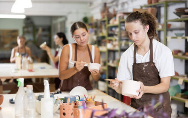Glad young guy and girl wearing apron are engaged in carpentry in art studio