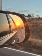 por do sol no retrovisor do carro na estrada