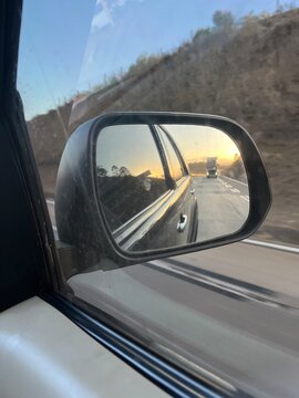 por do sol no retrovisor do carro na estrada