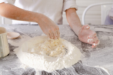 The hands of a young girl mixing flour and water for making a dough.