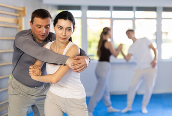 Woman practices blows to the head of a male attacker during self-defense training.