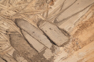 Close-up view of tire tracks and tread patterns imprinted in dry dirt at a construction site
