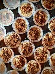 Overhead View of Tiramisu Desserts in Plastic Containers with Cocoa Powder.
