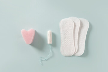 Female different tampons, daily pads on blue background. Hygiene accessories for women. View from above.
