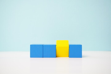 Yellow cube among blue cubes reflecting individuality or difference for educational or conceptual applications. strategy, business, economy and educational concepts