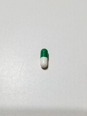 Green and white medication capsule