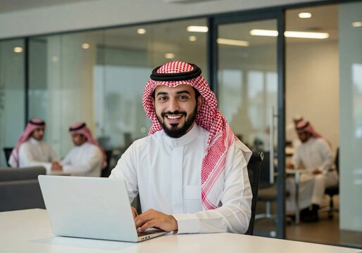 Middle eastern businessman smiling and working on a laptop in a modern office, representing success, technology, and Middle Eastern business culture. - Powered by Adobe