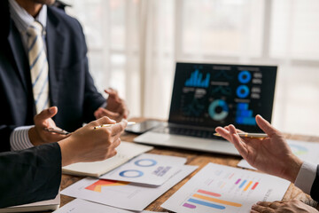 Business people discussing and analyzing financial charts and graphs using a laptop