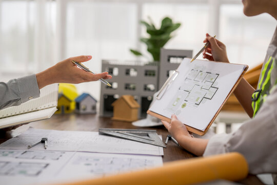 Architects discussing housing project with miniature house models and blueprint