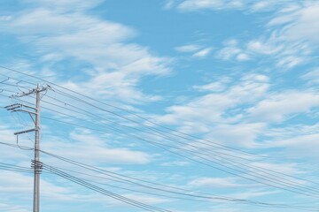 Power lines stretch against a pale blue sky dotted with wispy clouds