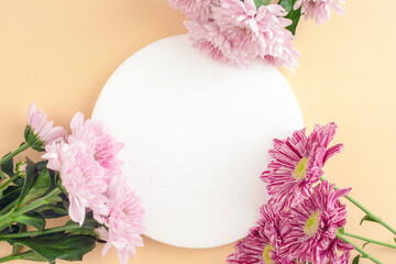 Beige background with white podium for cosmetic product, mockup. Daisy flowers decoration. Top...