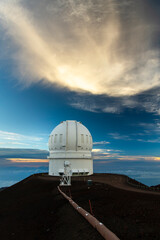 Sunset light illuminates the Mauna Kea Observatory on the Big Island of Hawaii, with dramatic...