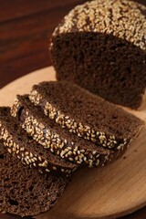 Pieces of fresh rye bread with seeds on wooden table, closeup