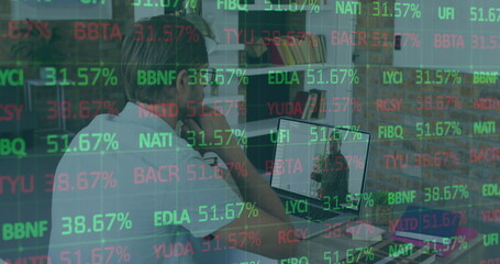 Sitting man gazing at laptop at home office, with glass partition reflecting tickers, copy space