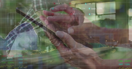 Senior hands tapping smartphone screen in modern office workspace, with ticker symbols and graphs