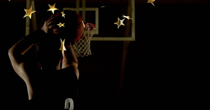 Naklejki Athlete wearing jersey 2 raising basketball overhead in gym, with hoop net, gold stars, copy space