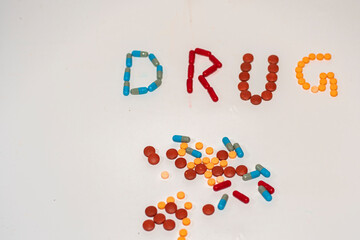 Drug Text with Medicine Pills on White Background for Modern Healthcare Concept
