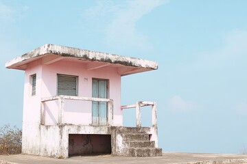 Pastel pink weather-beaten lookout hut on a hilltop, bathed in soft light