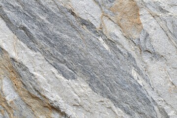 Close-up view of a stone surface with varied shades of gray, beige, and white.  Textured, rough surface with prominent diagonal lines