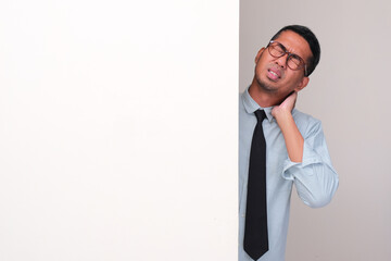 A businessman peeking behind wall suffering neck pain