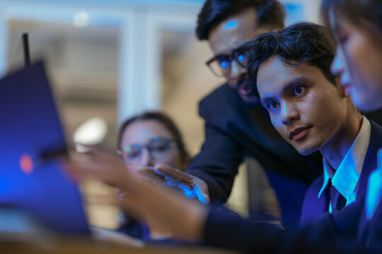 An Indian business manager leads his diverse team, analyzing critical market data on a screen. Intense focus on financial strategy and corporate decision making in a modern office.