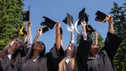 Young women of different nationalities pull graduation caps up. 