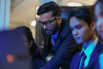 A senior AI architect mentors a diverse team as they debug a complex neural network. Intense,...