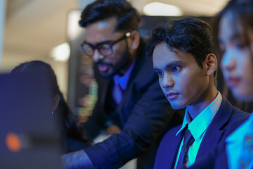 A senior AI architect mentors a diverse team as they debug a complex neural network. Intense,...