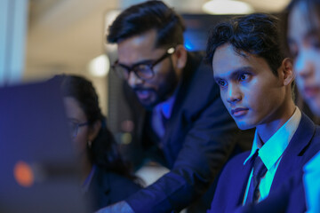 A senior AI architect mentors a diverse team as they debug a complex neural network. Intense,...