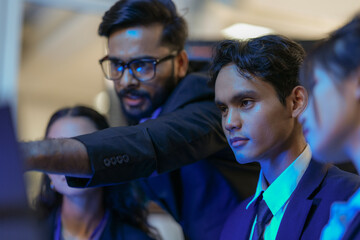 An Indian business manager leads his diverse team, analyzing critical market data on a screen....