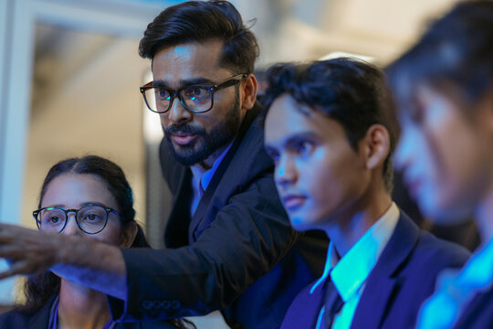 An Indian business manager leads his diverse team, analyzing critical market data on a screen. Intense focus on financial strategy and corporate decision making in a modern office.