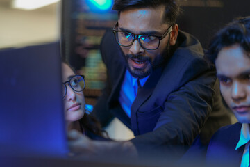 A senior AI architect mentors a diverse team as they debug a complex neural network. Intense, focused collaboration on developing the future of Artificial General Intelligence (AGI).