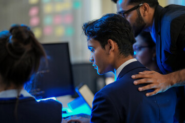 A senior AI architect mentors a diverse team as they debug a complex neural network. Intense, focused collaboration on developing the future of Artificial General Intelligence (AGI).