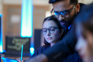 A senior AI architect mentors a diverse team as they debug a complex neural network. Intense,...