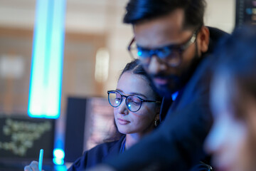 A senior AI architect mentors a diverse team as they debug a complex neural network. Intense, focused collaboration on developing the future of Artificial General Intelligence (AGI).