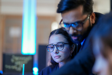 A senior AI architect mentors a diverse team as they debug a complex neural network. Intense,...