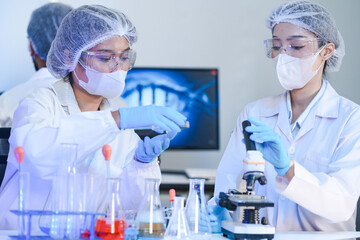 A diverse team of scientists collaborates in a high-tech biotech lab. A senior researcher mentors...