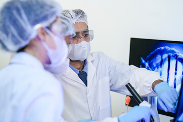A diverse team of scientists collaborates in a high-tech biotech lab. A senior researcher mentors...