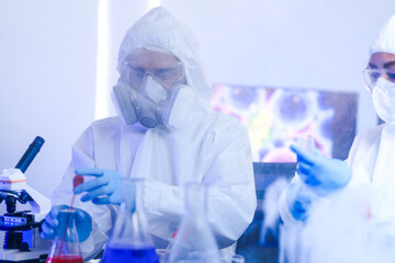 A diverse team of scientists collaborates in a high-tech biotech lab. A senior researcher mentors...