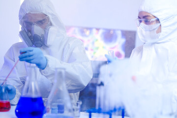 A diverse team of scientists collaborates in a high-tech biotech lab. A senior researcher mentors...