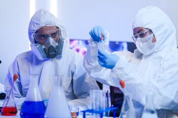 A diverse team of scientists collaborates in a high-tech biotech lab. A senior researcher mentors...