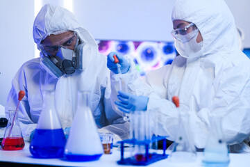 A diverse team of scientists collaborates in a high-tech biotech lab. A senior researcher mentors...