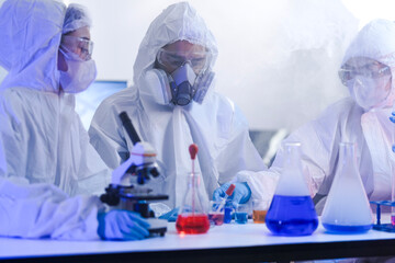 A diverse team of scientists collaborates in a high-tech biotech lab. A senior researcher mentors...