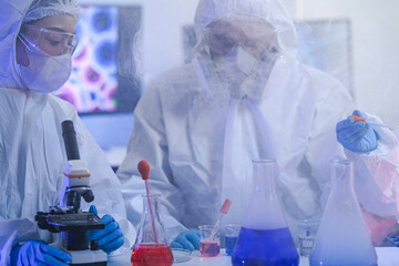 A diverse team of scientists collaborates in a high-tech biotech lab. A senior researcher mentors...
