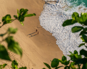 Stunning views of Nusa Penida Beach from above, with turquoise waves crashing onto the shore and...