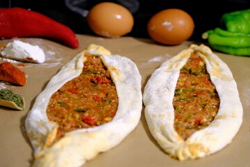Making ground meat pide, a traditional Turkish culinary delight. A housewife prepares ground meat pide. Eggs, green and red peppers. Healthy eating. Making pide at home. Turkish cuisine.