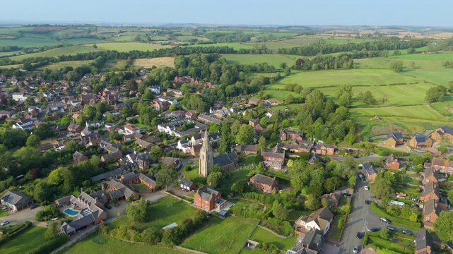 Aerial drone view over small quaint village in Leicestershire late evening light, houses and church, green rural landscape England UK European 