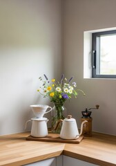 Cozy kitchen corner with fresh flowers, coffee set, and a wooden grinder by the window.