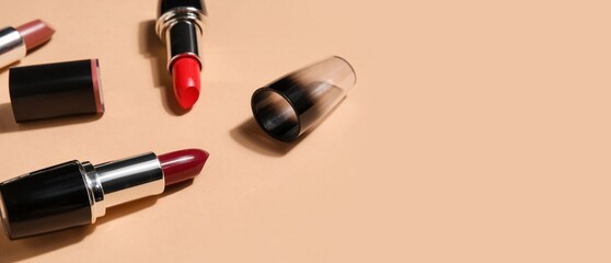 Different lipsticks on beige background with space for text, closeup